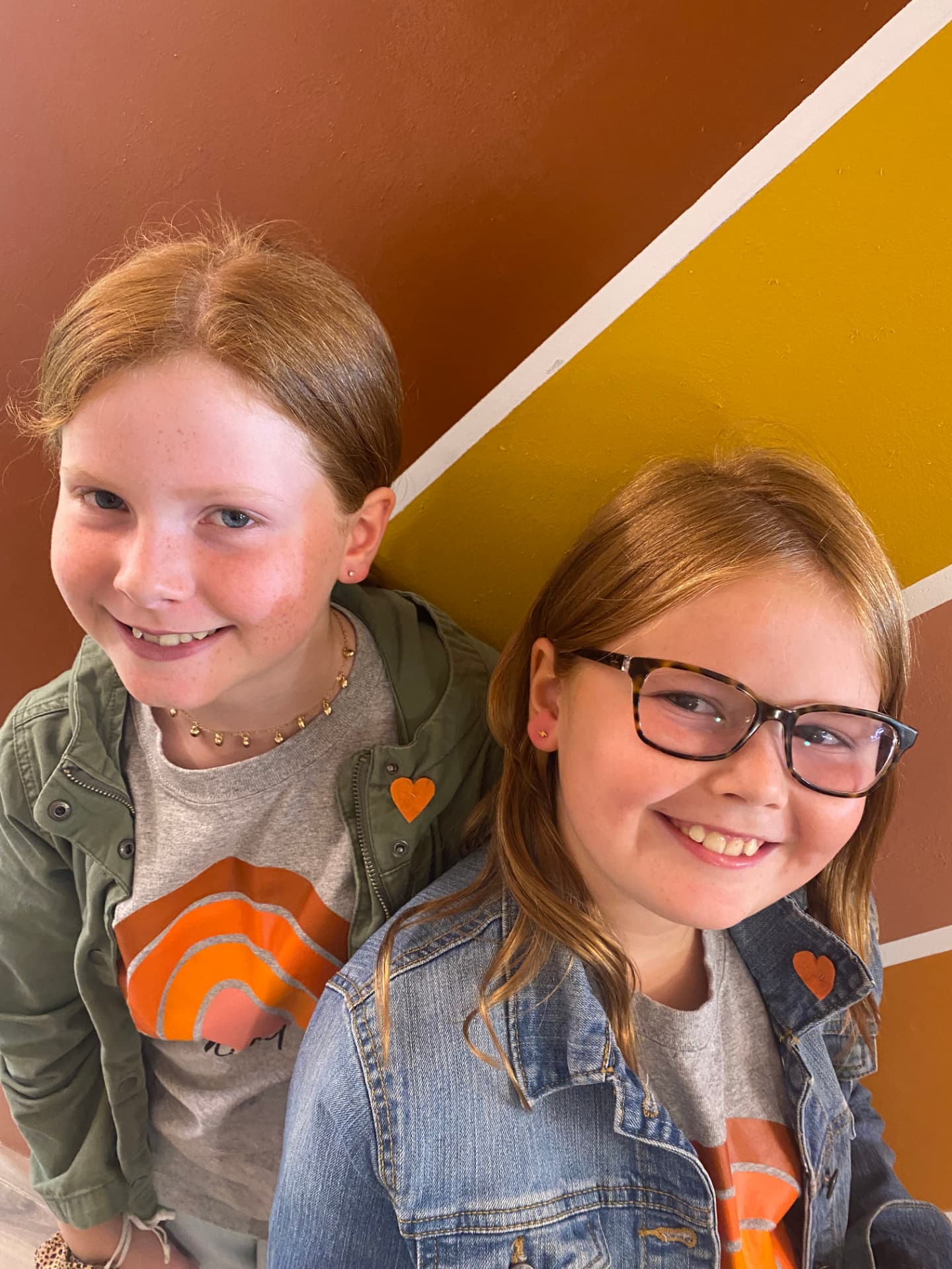 Two smiling kids in front of the warm sunburst wall