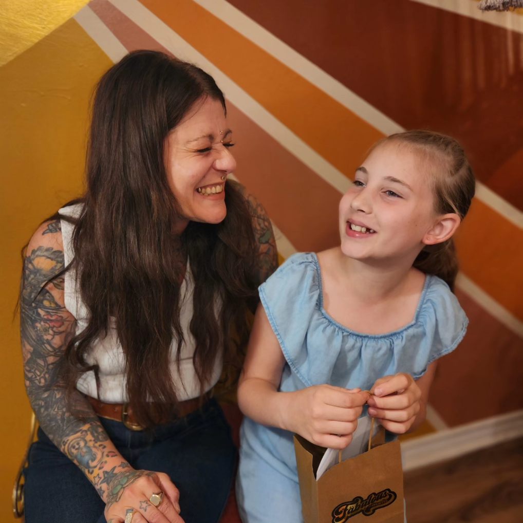 Juliette smiling with a young client in front of the warm sunburst wall